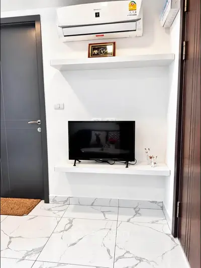 Modern living room corner with TV and air conditioning, sleek marble flooring, and minimalist decor.