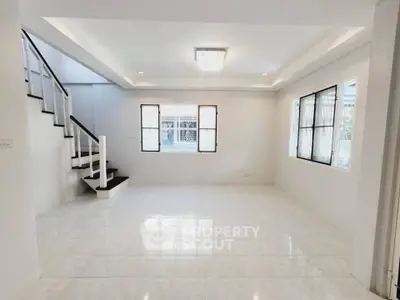 Spacious living room with elegant staircase and large windows