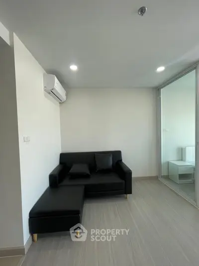 Modern living room with sleek black sofa and air conditioning in a minimalist apartment.