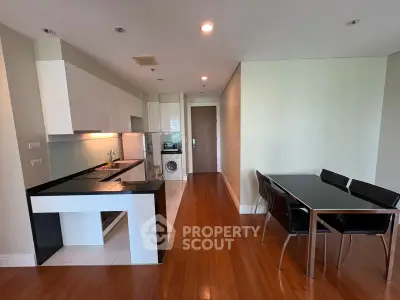 Modern kitchen with sleek design and dining area featuring hardwood floors and contemporary furniture.