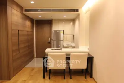 Modern kitchen with sleek design, featuring a compact dining area and stainless steel appliances.