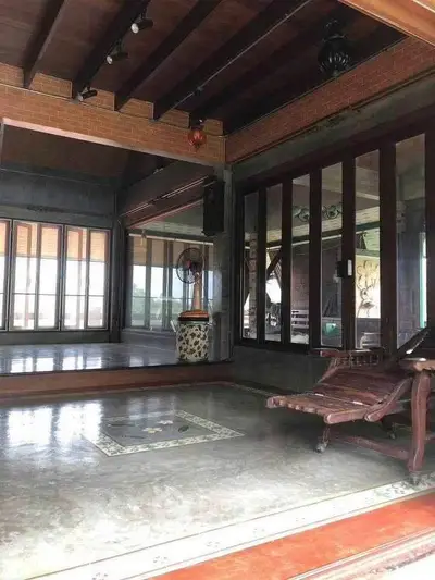 Spacious traditional living room with wooden beams and large windows, offering a serene ambiance.