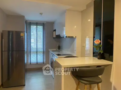 Modern kitchen with sleek design, featuring a breakfast bar and large window for natural light.