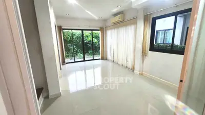 Spacious living room with large windows and garden view, perfect for natural light lovers.