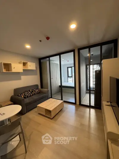 Modern living room with glass partition, cozy sofa, and stylish decor in a contemporary apartment.