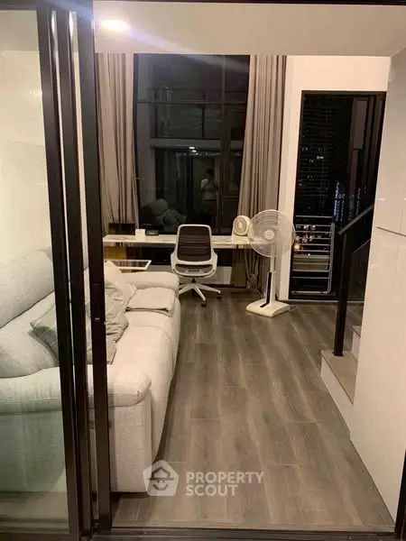Modern living room with sleek design and study area, featuring large windows and stylish furniture.
