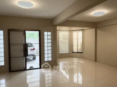 Spacious modern living room with large windows and sleek tile flooring, perfect for natural light lovers.
