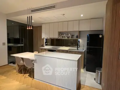 Modern kitchen with sleek design, featuring an island, dining area, and contemporary appliances.