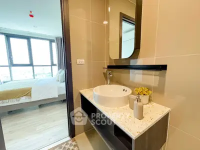 Modern bathroom with stylish sink and mirror, adjacent to a bright bedroom with large windows.