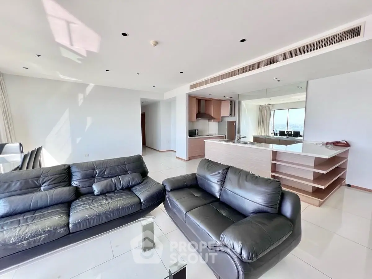 Spacious modern living room with open kitchen and sleek leather sofas