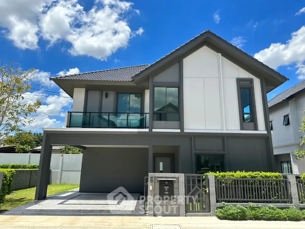Modern two-story house with sleek design and spacious driveway under a clear blue sky.