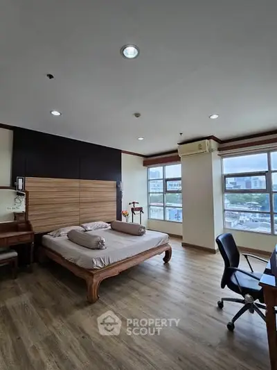Spacious bedroom with large windows and modern furnishings in a high-rise apartment.