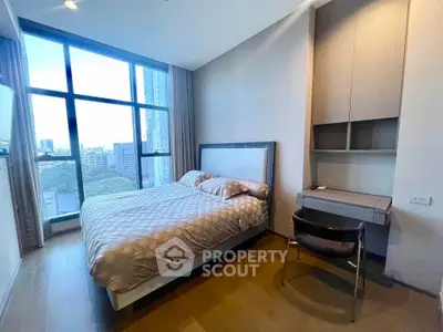 Modern bedroom with large window and city view, featuring a cozy bed and built-in desk.