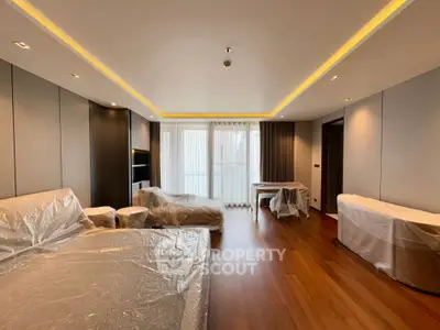 Spacious modern living room with floor-to-ceiling windows and elegant wood flooring.