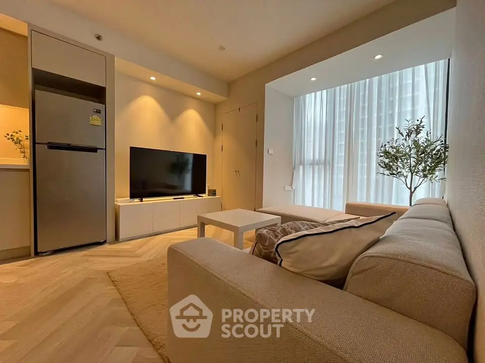 Modern living room with cozy beige sofa, flat-screen TV, and stylish decor in a bright apartment.