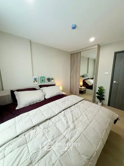 Modern bedroom with cozy bedding and mirrored wardrobe in stylish apartment.