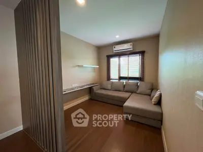 Modern living room with cozy sectional sofa and air conditioning, featuring warm wooden flooring and stylish blinds.