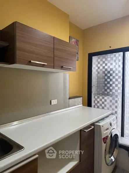 Modern kitchen with sleek cabinets and washing machine in cozy space.