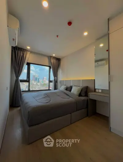 Modern bedroom with city view, featuring cozy bed and stylish decor in high-rise apartment.