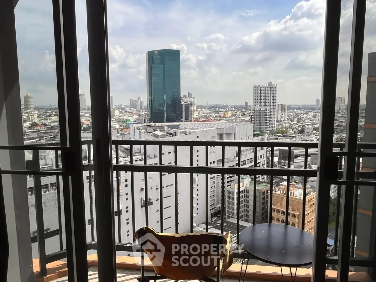 Stunning cityscape view from a modern balcony with seating area.