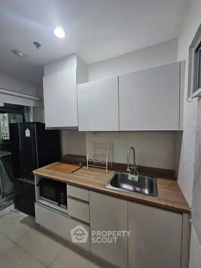Modern kitchen with sleek cabinetry and stainless steel sink, featuring a compact layout and contemporary design.