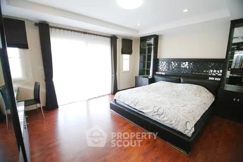 Spacious bedroom with elegant decor and large windows for natural light.