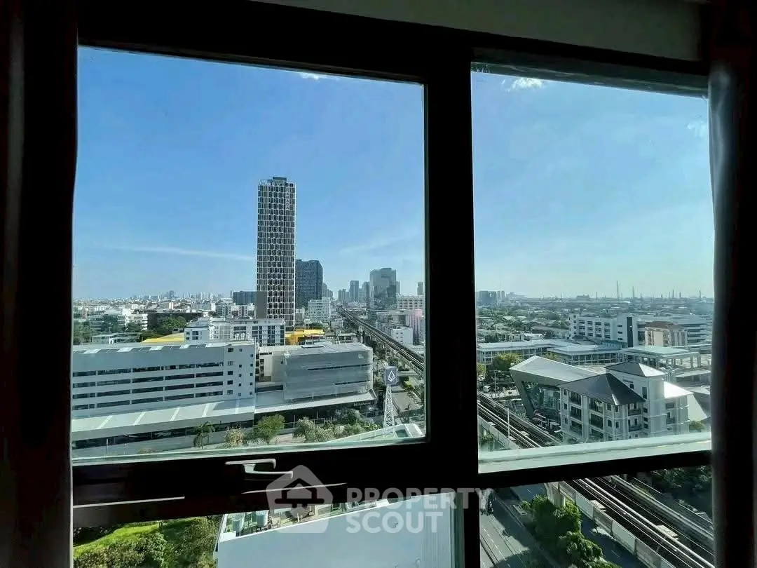 Stunning cityscape view from high-rise apartment window, showcasing urban skyline and blue skies.