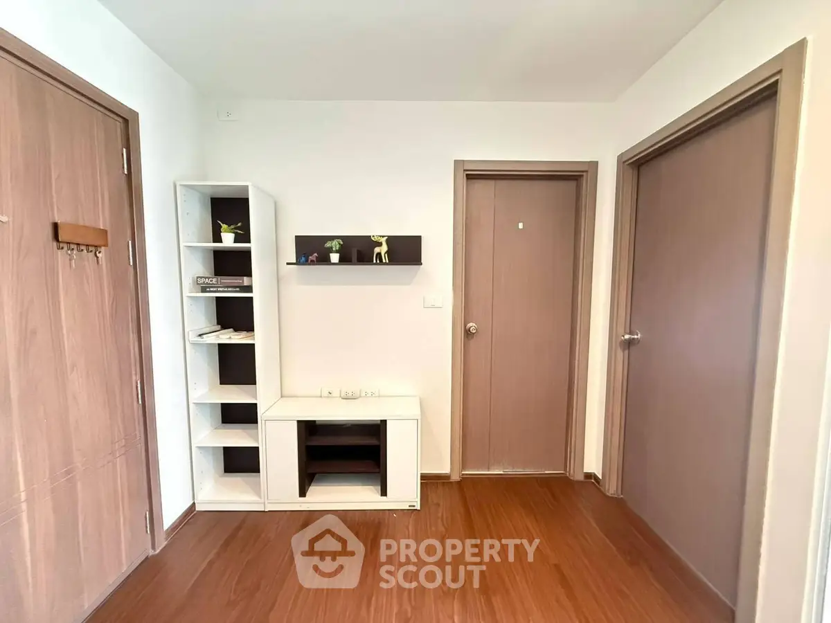 Modern apartment hallway with wooden flooring and minimalist shelving unit.
