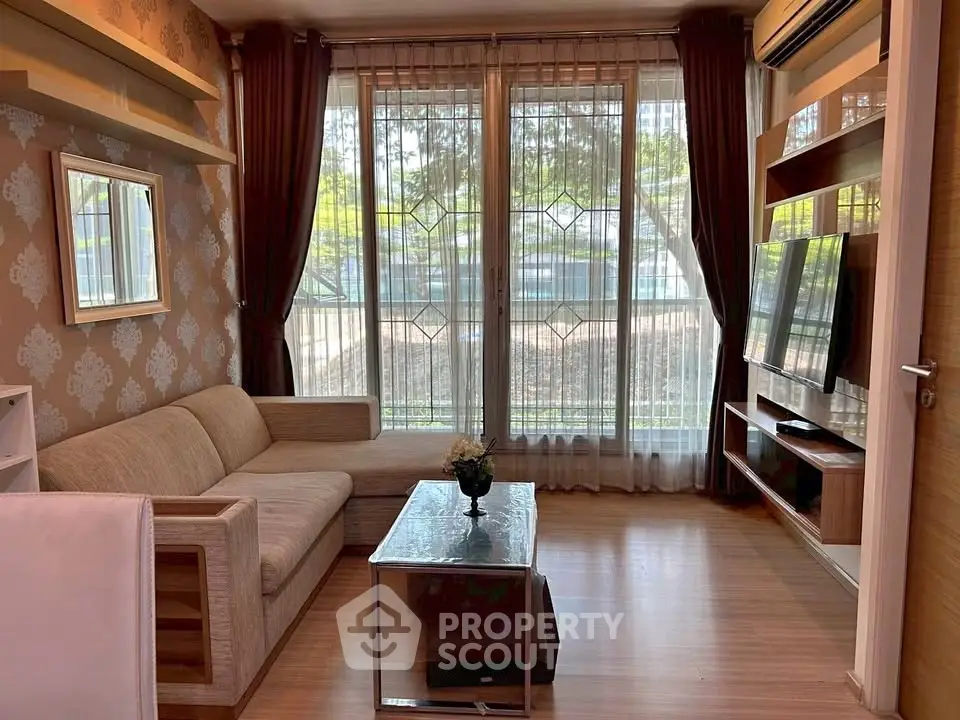 Cozy living room with large windows, modern sofa, and wall-mounted TV in a stylish apartment.