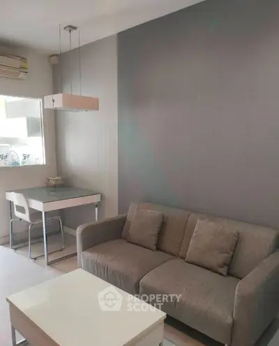 Modern living room with sleek gray sofa and stylish dining area in open layout apartment.