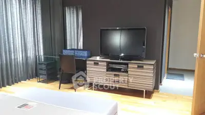 Modern bedroom with sleek TV stand and glass desk, perfect for stylish living.