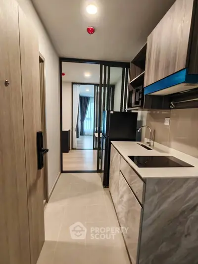 Modern compact kitchen with sleek cabinetry and integrated appliances in a stylish apartment.