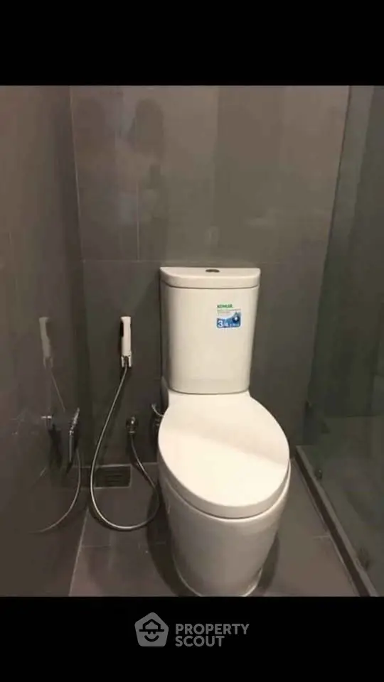 Modern bathroom with sleek toilet and bidet spray in a contemporary setting.