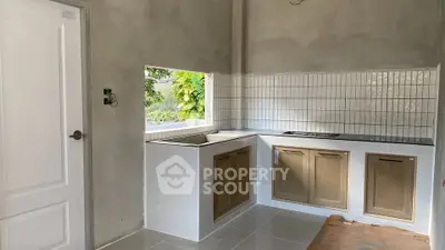 Modern kitchen with sleek cabinetry and tiled backsplash in a bright, unfinished space.