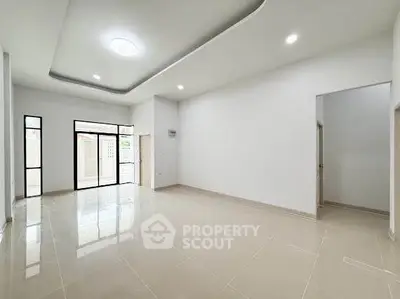 Spacious modern living room with large windows and sleek tile flooring.