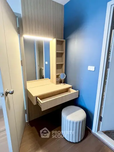 Modern bedroom with stylish vanity and stool, featuring elegant wood paneling and blue accent wall.