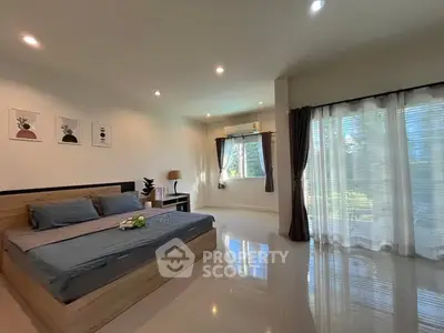 Spacious bedroom with large windows and modern decor, offering a serene and inviting atmosphere.