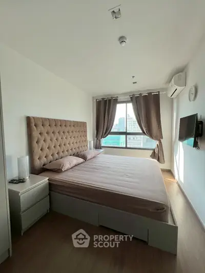 Spacious bedroom with city view, modern furnishings, and natural light.
