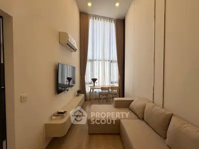 Modern living room with high ceilings, large windows, and stylish furniture in a contemporary apartment.