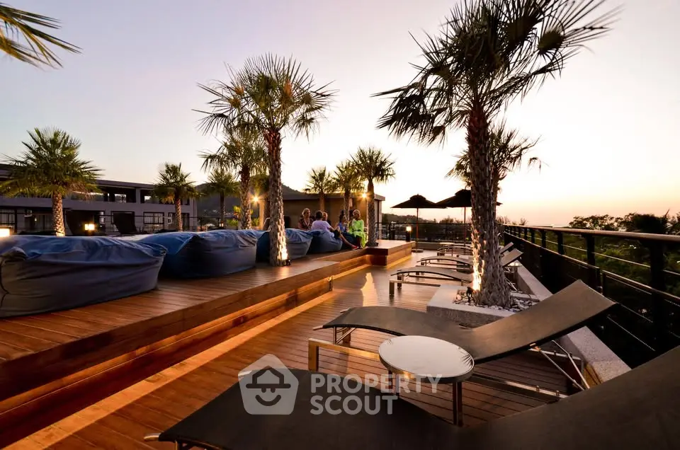 Luxurious rooftop terrace with sunset view, palm trees, and modern lounge chairs.
