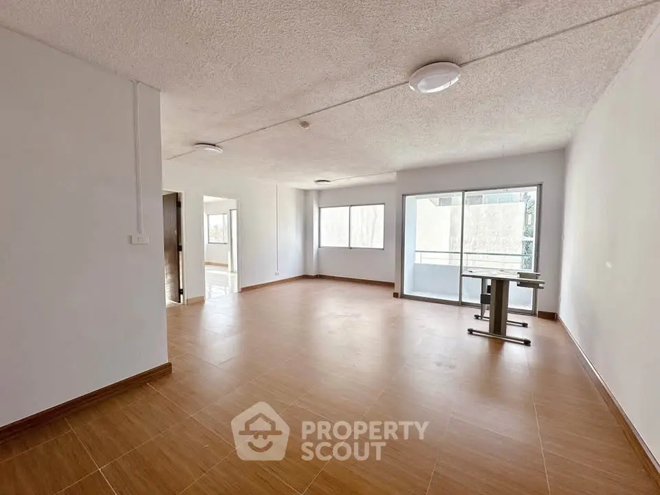 Spacious unfurnished living room with large windows and balcony access.