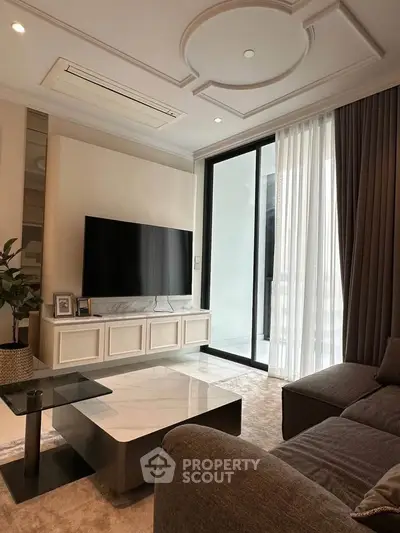 Elegant living room with modern decor, large TV, and floor-to-ceiling windows for natural light.