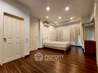 Spacious bedroom with wooden flooring and modern lighting