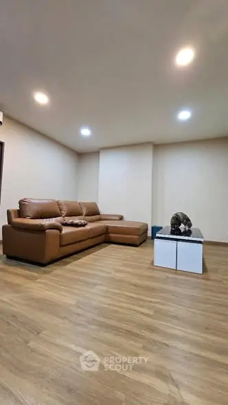 Spacious living room with modern leather sofa and wooden flooring