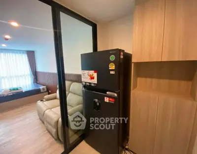 Modern apartment interior with cozy living room and sleek kitchen area featuring a stylish fridge.