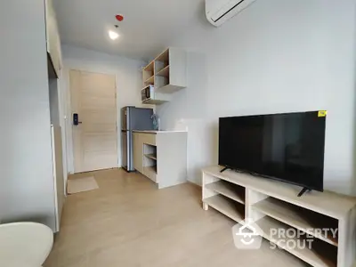 Modern studio apartment with compact kitchen and sleek TV setup