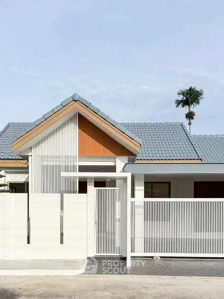 Modern minimalist house exterior with unique roof design and sleek white fence.