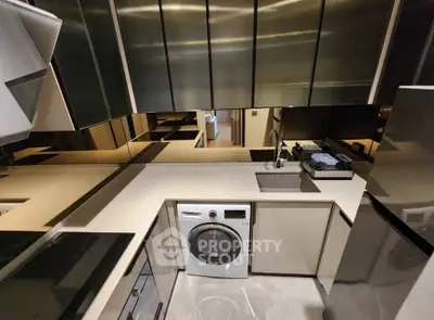 Modern kitchen with sleek appliances and washer in compact layout