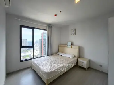 Modern bedroom with large window and city view, featuring minimalist decor and natural light.