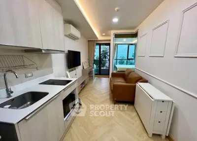 Modern open-layout living room with kitchen, featuring sleek design and natural light from large windows.